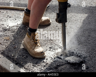 Workman à l'air comprimé marteau pneumatique à découper tarmac couvert chemin de béton pour localiser les services de métro London England UK Banque D'Images