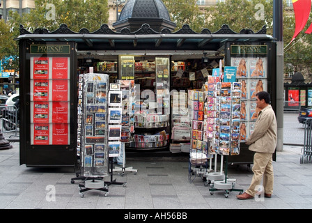 Paris Avenue champs Elysées carte postale affichée sur les supports de magazines et journaux Spinners dans le kiosque client sur le trottoir en France Europe Banque D'Images