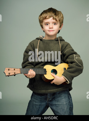 Garçon faisant semblant d'être une rock star avec petite guitare ukulele ukelel childs Banque D'Images