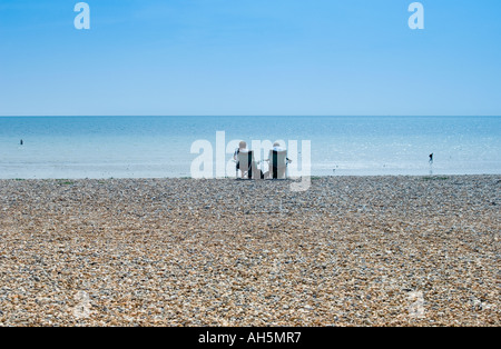 Deux touristes assis sur une plage de galets à Worthing, Angleterre du sud, avec vue sur la mer et l'horizon à distance Banque D'Images