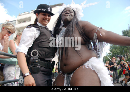 Policewoman interagissant et posant avec très grand danseur noir à Notting Hill Carnival. Banque D'Images