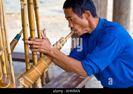 Dong homme jouant de la Flûte en bois traditionnels complexes Zhaoxing Chine Banque D'Images
