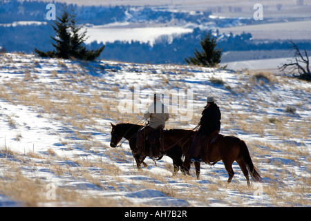 Deux hommes de l'équitation dans un champ couvert de neige Banque D'Images