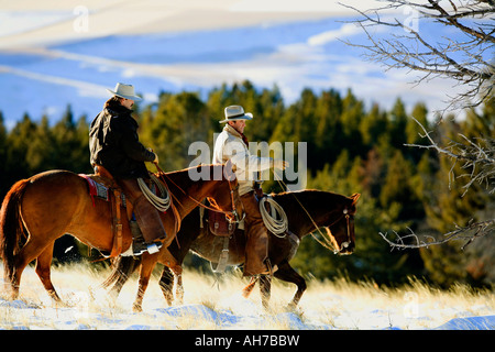 Deux hommes de l'équitation dans un champ couvert de neige Banque D'Images