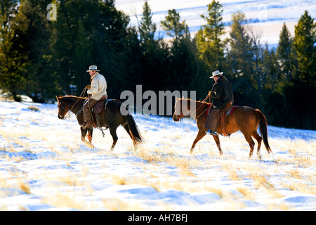 Deux hommes de l'équitation dans un champ couvert de neige Banque D'Images