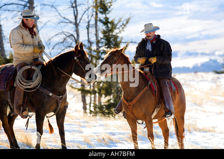 Deux hommes de l'équitation dans un champ couvert de neige Banque D'Images