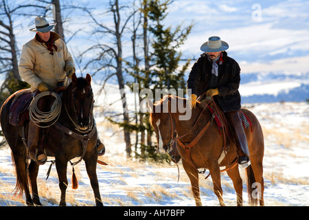 Deux hommes de l'équitation dans un champ couvert de neige Banque D'Images