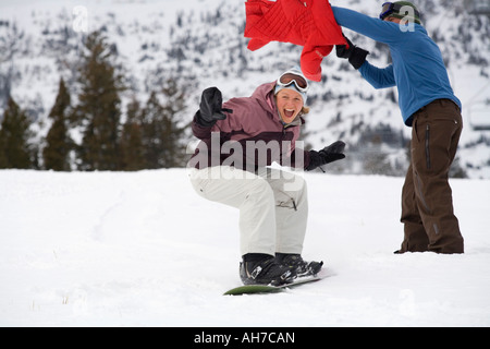 Mid adult woman snowboarding passé a Mid adult man Banque D'Images