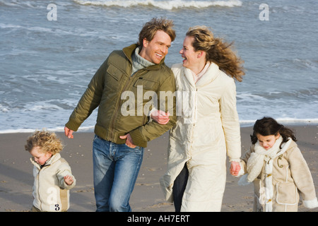 Couple marchant avec leur fils et fille sur la plage