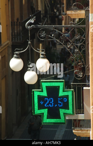 Tarragone électronique croix verte pharmacie affiche de magasin de pharmacie avec la température affichée numériquement avec des feux de rue au-dessus de Catalogne Espagne Banque D'Images