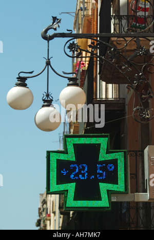 Tarragone électronique croix verte pharmacie affiche de magasin de pharmacie avec la température affichée numériquement avec des feux de rue au-dessus de Catalogne Espagne Banque D'Images