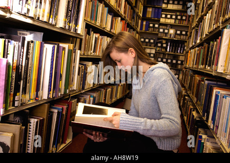 Jeune femme recherche à travers des livres sur les rayons de bibliothèque Bibliothécaire Banque D'Images