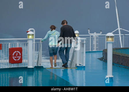 Un couple de passagers pendant un jour de pluie sur le pont extérieur d'un bateau sous un temps orageux Banque D'Images
