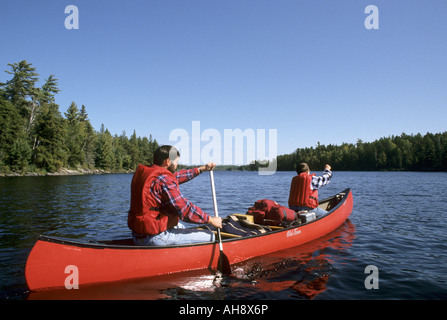 Père et Fils LEUR PADDLE RED CANOE SUR LE LAC DE L'UN, Boundary Waters Canoe Area Wilderness, N.E. MINNESOTA, États-Unis d'automne. Banque D'Images