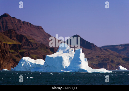 Gros iceberg contrastant contre les falaises de l'île Disko stérile sur la mer de glace au large de Qeqertarsuaq sur côte ouest du Groenland Banque D'Images