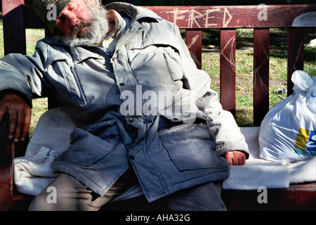 Homme endormi sur un banc dans le parc Banque D'Images