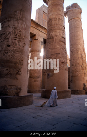 Premières heures du matin, Temple de Karnak Louxor en Égypte un homme avec un balai de nettoyage de finition le site avant l'arrivée des touristes Banque D'Images