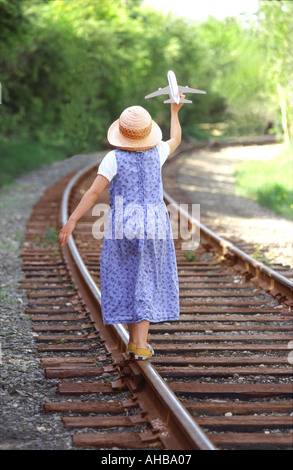 Jeune fille de 10 ans marche sur voie ferrée Playing with toy airplane Banque D'Images