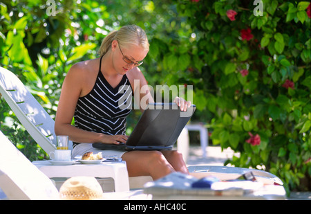 Jeune femme blonde travaillant avec lap top piscine assis sur une chaise longue à Olu Deniz, Turquie. Banque D'Images