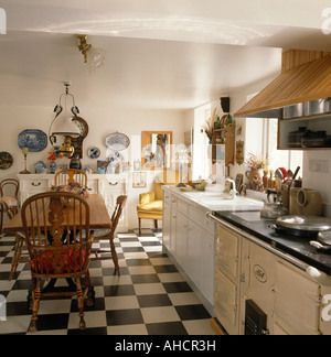 Damier noir et blanc revêtement en vinyle en pays blanc d'une cuisine avec table en bois et chaises Windsor et Aga crème Banque D'Images