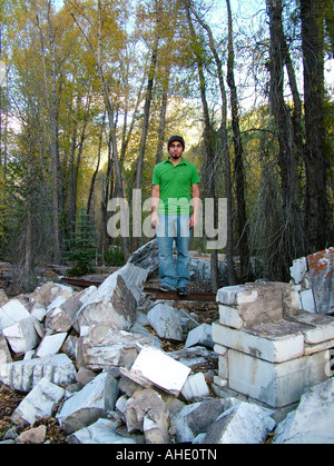 Un homme d'origine hispanique dans une chemise verte debout sur une rampe en fer sur une pile de blocs de marbre au Colorado Yule en entreprise, CO, USA Banque D'Images