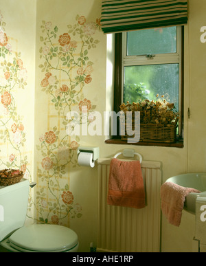 Panier de fleurs séchées sur le rebord de la petite salle de bains avec 90 roses au pochoir sur les murs Banque D'Images