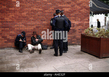 L'arrêt de la police communautaire et la mise en cause des hommes sans-abri assis boire dans le centre de Londres. Banque D'Images