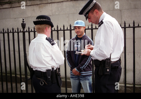 Des jeunes qui sont arrêtés et fouillés par la police sur Whitehall, au centre de Londres. Banque D'Images