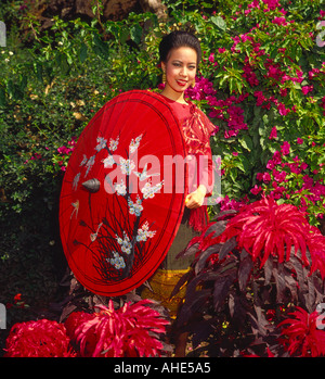 Pretty dark haired young attractive Thai girl holding parasol traditionnel à Chiang Mai dans le Nord de la Thaïlande Banque D'Images