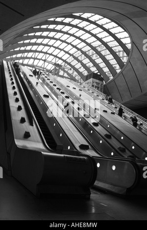 Photographie en noir et blanc des navetteurs sur les escaliers mécaniques à la station de métro Canary Wharf, les Docklands, Londres, Angleterre Banque D'Images