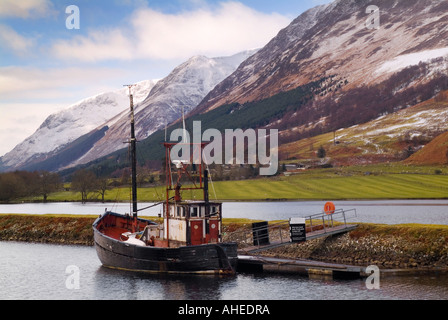 Une photo de paysage écossais en hiver avec les montagnes enneigées avec un chalutier amarré à un lochside Banque D'Images