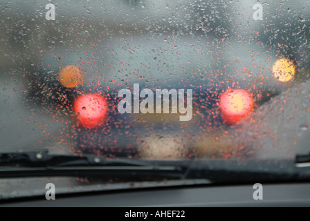 Feux arrière de voiture en avant dans de mauvaises conditions météorologiques de la neige et la pluie verglaçante Banque D'Images