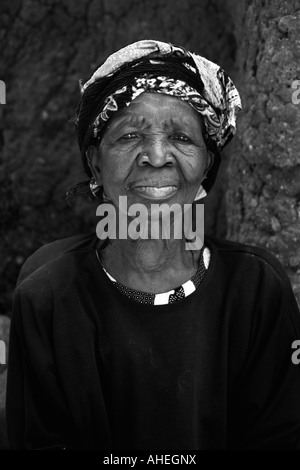 Senior African woman avec la tête enveloppée d'écharpe du regard et d'étudier. Banque D'Images