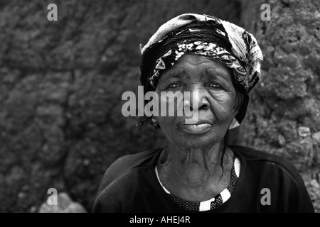 Senior African woman avec la tête enveloppée d'écharpe du regard et d'étudier. Banque D'Images