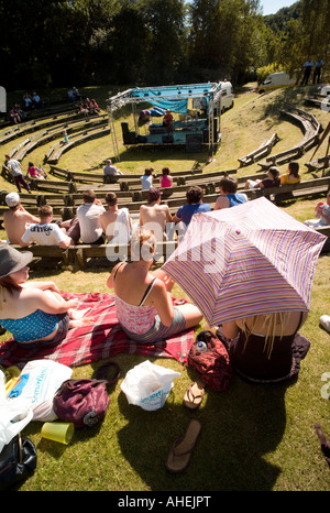 Les jeunes gens assis au soleil à regarder les artistes interprètes ou exécutants au Rock 'Le lac' free concert pop Rhayader Powys Août 2007 Banque D'Images