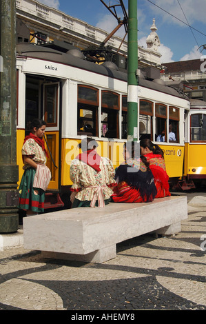 Les jeunes femmes en costume traditionnel assis à côté de tramway jaune à Praca do Comercio square, Lisbonne Portugal Banque D'Images