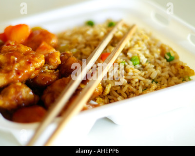 Chinois à emporter la nourriture (Général bsf Poulet et riz frit) en polystyrène blanc avec des baguettes en bambou, dans l'accent peu profondes. Banque D'Images