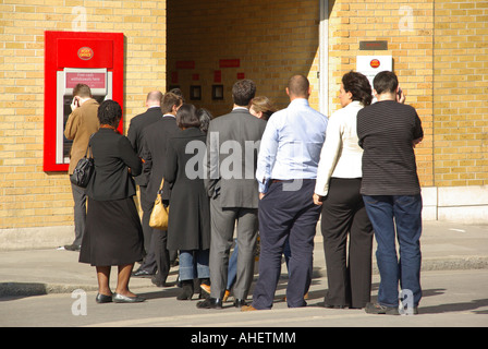 Le temps du déjeuner file d'attente arrière voir les personnes qui attendent de retirer leur argent du trou dans le distributeur de billets mural à l'extérieur du bureau de poste City de Londres Angleterre Royaume-Uni Banque D'Images