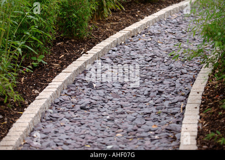 Un chemin organisé avec des éclats d'ARDOISE GRANIT BORDÉE DE GALETS ET LES LITS PLANTÉS DE JEUNES NOIR ORIENTAL BAMBOO PHYLLOSTACHYS UK Banque D'Images