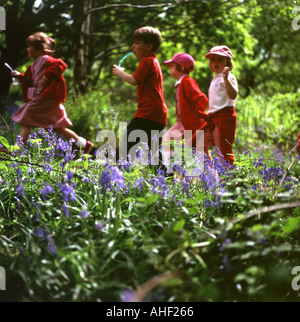 Jardin d'enfants de l'école maternelle les enfants de l'école fonctionnent à l'extérieur à travers des cloches dans Une forêt au printemps Carmarthenshire pays de Galles Royaume-Uni KATHY DEWITT Banque D'Images