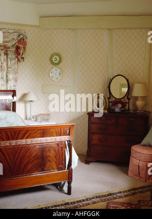 Lit ancien en pays chambre avec commode en acajou et papier peint en treillis Banque D'Images