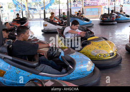 Deux garçons de l'âge de l'adolescence sur les pare-chocs des voitures entrent en collision dans un parc d'Attractions en Californie Banque D'Images