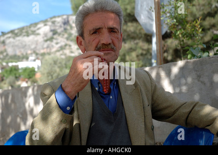 Portrait d'un homme âgé avec perles retrouvez assis à bar dans le sud du village turc. Banque D'Images