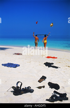 Couple de lancer lors de l'exécution de l'ensemble de vêtements côte de sable blanc vers le bleu de l'océan sur premier jour de vacances de l'île Banque D'Images