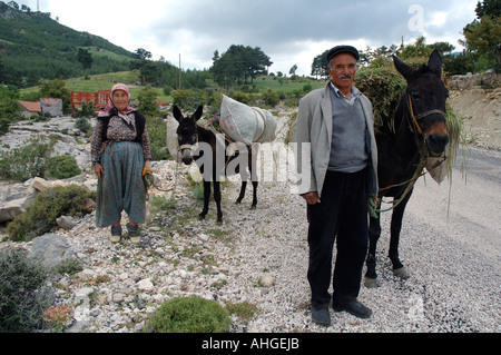 L'homme et de la femme turque sur la route avec leur âne chargé vers le haut avec les récoltes dans les collines de l'Anatolie du sud de la Turquie. Banque D'Images