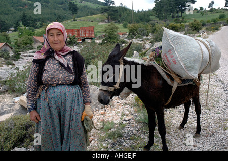 L'homme et de la femme turque sur la route avec leur âne chargé vers le haut avec les récoltes dans les collines de l'Anatolie du sud de la Turquie. Banque D'Images