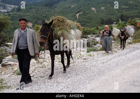 L'homme et de la femme turque sur la route avec leur âne chargé vers le haut avec les récoltes dans les collines de l'Anatolie du sud de la Turquie. Banque D'Images