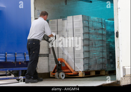 Ouvriers déchargement camion plateau élévateur contenant palette enveloppée des piles de boîtes de système informatique pour le nettoyage des données et de recyclage Banque D'Images