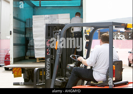 Ouvriers déchargement camion avec plateau élévateur chariot contenant palette enveloppée des piles de boîtes de système informatique au Royaume-Uni Banque D'Images