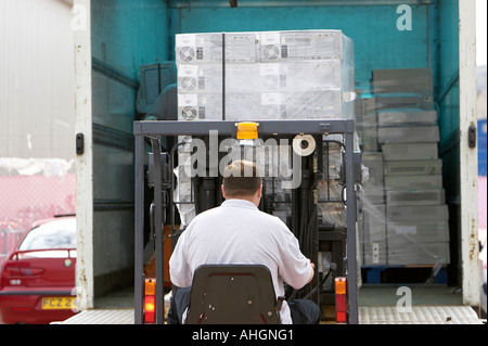 Ouvriers déchargement camion avec plateau élévateur chariot contenant palette enveloppée des piles de boîtes de système informatique Banque D'Images